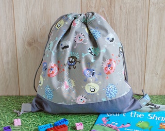 Mini mochila infantil con cordón gris y divertidos monstruos