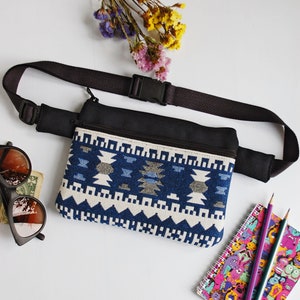 May include: A blue and white patterned fanny pack with a black adjustable strap. The fanny pack has two zippered compartments.