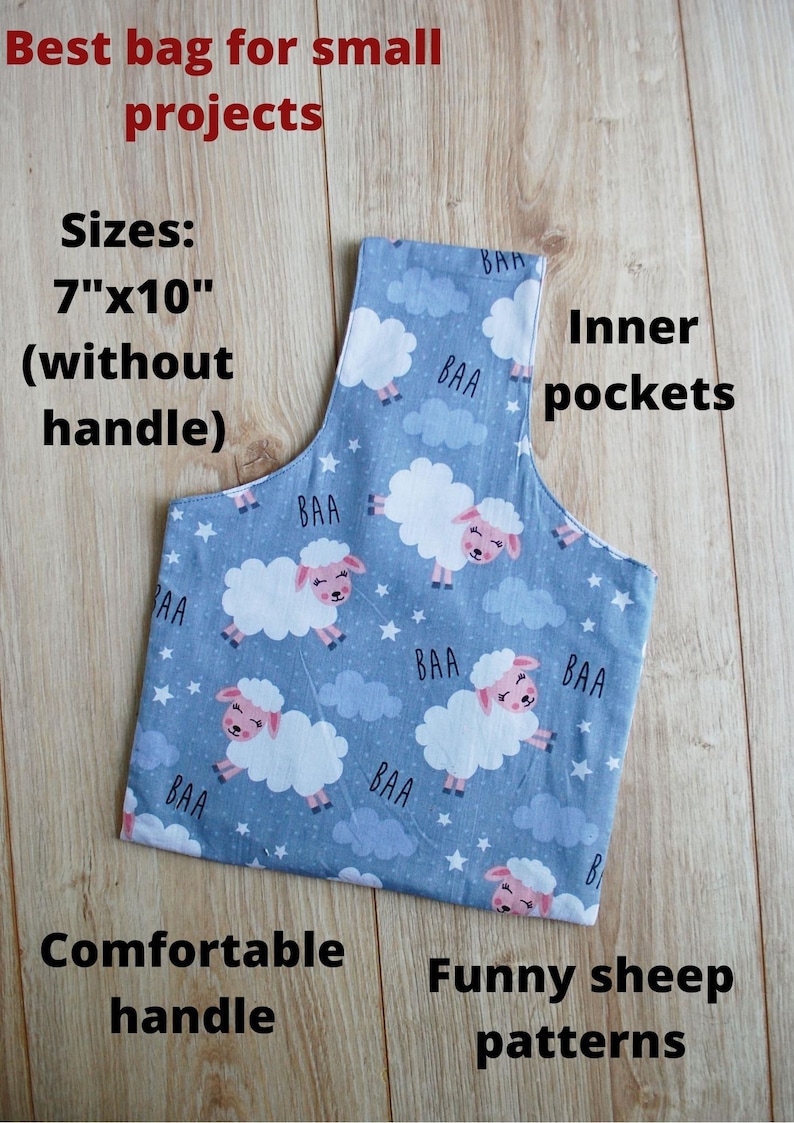 Pode incluir: Uma bolsa de tecido azul com um padr&atilde;o de ovelhas e as palavras "BAA" impressas nela. A bolsa tem uma al&ccedil;a confort&aacute;vel e bolsos internos. A bolsa mede 17,8 cm por 25,4 cm sem a al&ccedil;a.