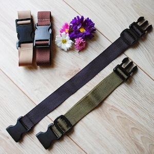 May include: Two brown and one beige adjustable straps with black plastic buckles. Two green and black adjustable straps with black plastic buckles. A bouquet of purple, pink, and white flowers.