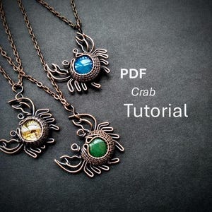 May include: Three handmade crab pendant necklaces with copper wire frames and gemstone centers in blue, yellow, and green. The necklaces are on a dark background. Text on the right reads "PDF Crab Tutorial".