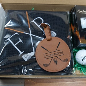 Coffret cadeau golf personnalisé. Comprend une serviette de golf, un jeu de trois balles de golf Pro V1 avec des monogrammes et une étiquette de sac de golf avec support pour tee