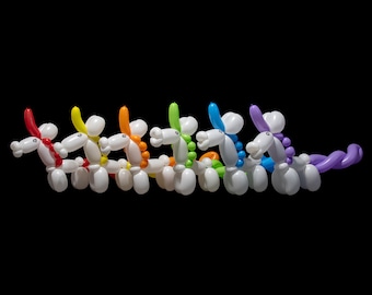 A rainbow of colorful balloon animal unicorns lined up on a black background
