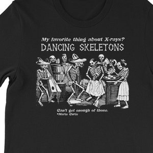 May include: Black t-shirt with a white graphic of dancing skeletons. The text reads "My favorite thing about X-rays? DANCING SKELETONS. Can't get enough of those. *Marie Curie"