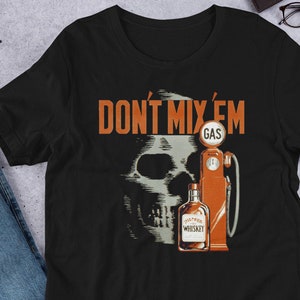 May include: Black t-shirt with a skull and crossbones graphic. The skull is behind a gas pump and a bottle of whiskey. The text "Don't Mix 'Em" is above the graphic.