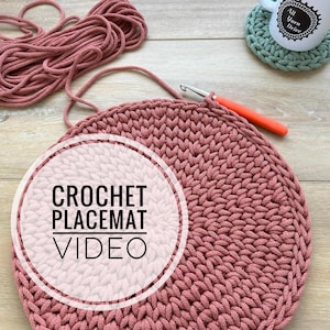 May include: A close-up of a pink crocheted placemat with a white circle around the text "CROCHET PLACEMAT VIDEO".