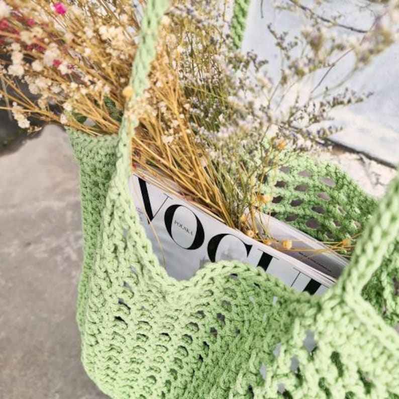 May include: A green crocheted tote bag with a magazine inside. The magazine is titled "Vogue Polska".