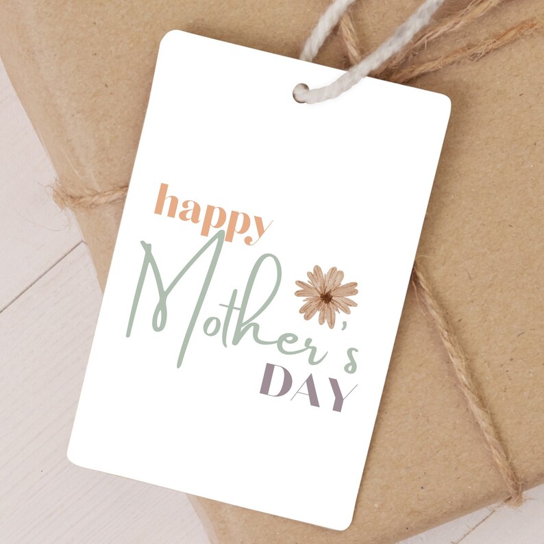 May include: White gift tag with the text "happy Mother's Day" in green, orange, and purple lettering. A small brown flower is to the right of the text.