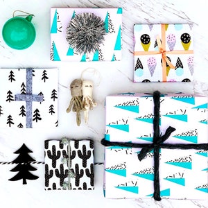 May include: Assortment of gift wrap featuring various patterns, including geometric shapes, trees, and cacti. The wrapping paper is in black, white, blue, pink, and green.