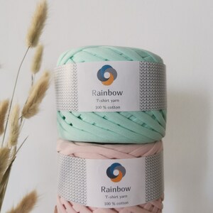 May include: Two spools of t-shirt yarn, one in light green and one in pink. Both spools have a white label with the text "Rainbow T-shirt yarn 100% cotton".