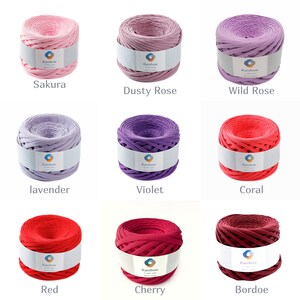 May include: Nine spools of rainbow yarn in various shades of pink, purple, and red. The yarn is made of cotton and is perfect for crocheting or knitting.