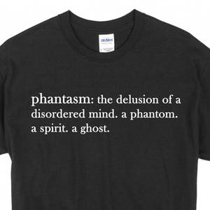以下が含まれることがあります： 白い文字で「phantasm: the delusion of a disordered mind. a phantom. a spirit. a ghost.」と書かれた黒いTシャツ