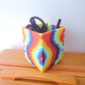 Puede incluir: Un organizador de cuentas con un patrón de arcoíris colorido con un bolígrafo negro y un par de tijeras negras en su interior.