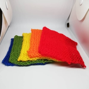 Pode incluir: Cinco quadrados de crochê em cores do arco-íris, empilhados uns sobre os outros. Os quadrados são azul, verde, amarelo, laranja e vermelho.