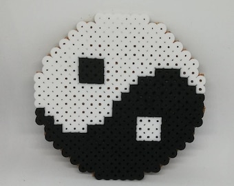 Puede incluir: Un símbolo yin yang en blanco y negro hecho de pequeñas cuentas redondas.