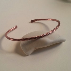 May include: A twisted copper bracelet with a smooth, polished finish.