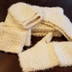 May include: A set of white crocheted mittens and a hat. The mittens and hat are made with a fluffy yarn.
