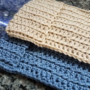 May include: Two crocheted dishcloths, one in a light beige color and the other in a light blue color. Both dishcloths have a textured pattern.