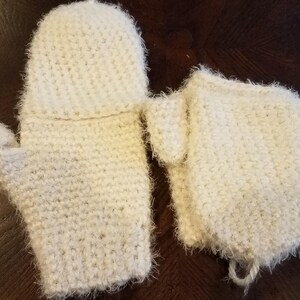 May include: A pair of white crocheted mittens with a fuzzy texture. One mitten has a fingertip and the other is a fingerless mitten.
