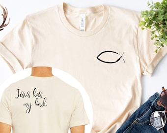 May include: A beige t-shirt with a fish symbol on the front and the text "Jesus has my back." on the back.