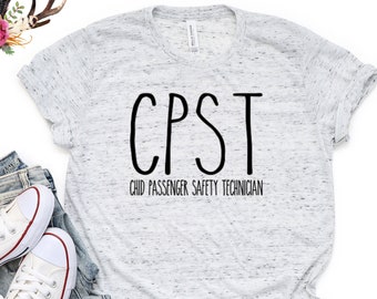 May include: A white t-shirt with a black graphic that says "CPST Child Passenger Safety Technician". The shirt is on a white background with a pair of white sneakers and blue jeans.