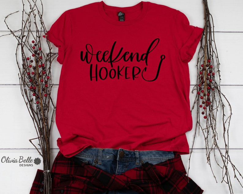 Peut inclure: T-shirt rouge avec le texte "Weekend Hooker" en lettres cursives noires avec un hame&ccedil;on &agrave; la fin du mot "Hooker".