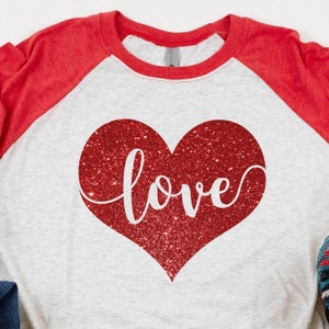 May include: A white and red baseball tee shirt with a red glitter heart and the word "love" in white script.