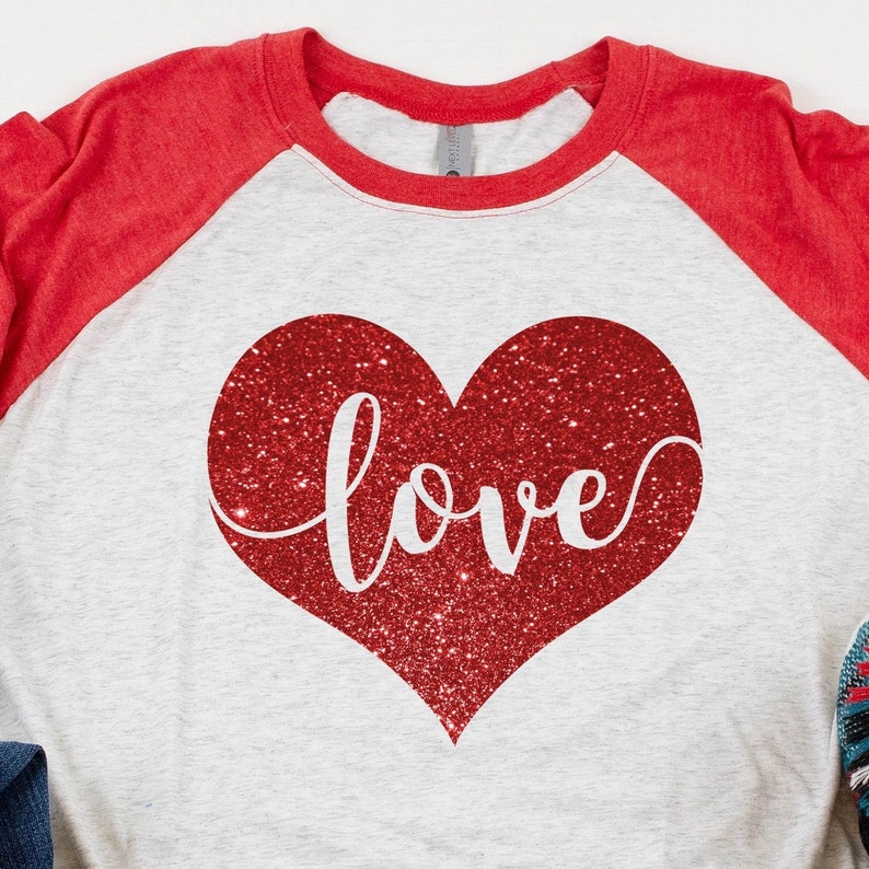 May include: A white and red baseball tee shirt with a red glitter heart and the word "love" in white script.