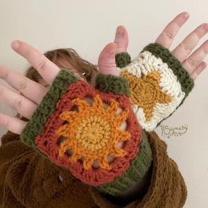 May include: Crocheted fingerless gloves featuring a sunburst design. The gloves are primarily orange, yellow, and white, with green trim. The design is a square pattern, and the gloves are shown on a person's hands.