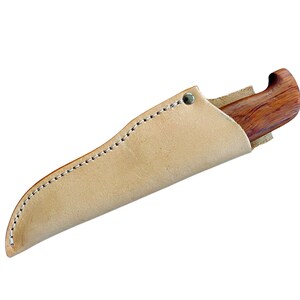May include: A handcrafted knife with a wooden handle and a leather sheath. The knife handle is a rich brown color, and the sheath is a light tan color. The sheath is stitched with white thread and has a metal rivet.