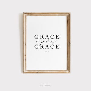 May include: A framed print with a white background and black text that reads "GRACE upon GRACE" with the scripture reference "JOHN 1:16" below.