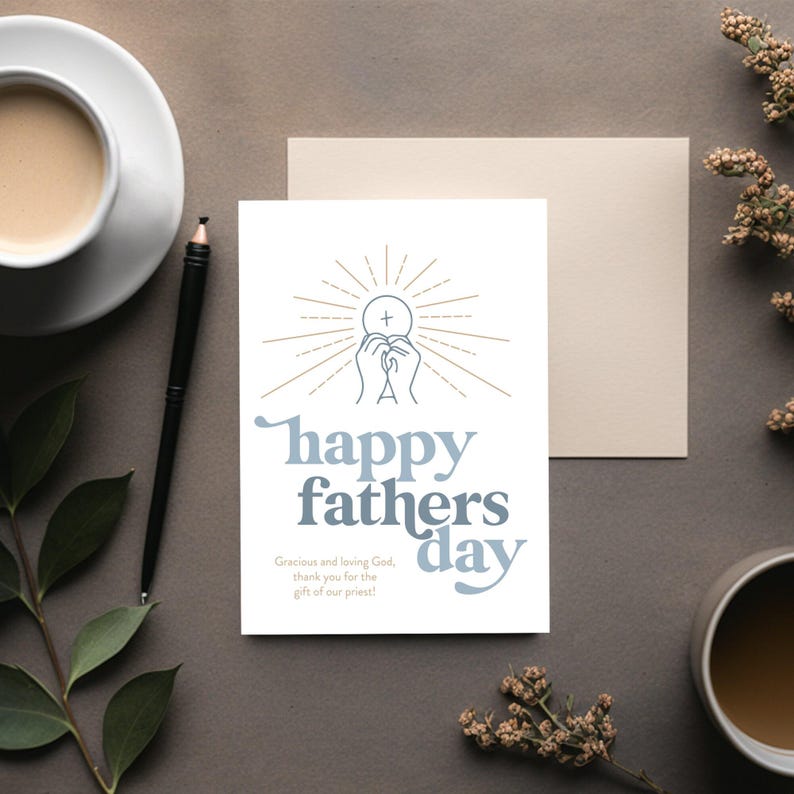 A white greeting card with "happy fathers day" and a communion host graphic is on a dark gray surface, with a pen, coffee, and dried flowers.