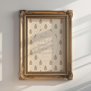 Puede incluir: Una pieza de arte mural rectangular en un marco dorado antiguo y ornamentado. La impresión presenta un fondo crema con un patrón de diamantes florales marrones repetidos. Centrado hay un óvalo que contiene el texto: Don't judge each day by the harvest you reap, but by the seeds that you plant.