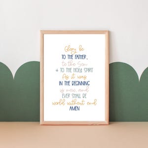 May include: A framed print with a white background and a navy blue and gold text that reads "Glory be to the Father, to the Son, & to the Holy Spirit. As it was in the beginning is now, and ever shall be world without end. Amen."