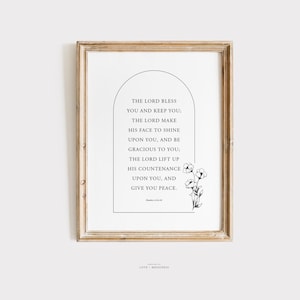 May include: Black and white printable wall art featuring a quote from Numbers 6:24-26. The quote reads "The Lord bless you and keep you: The Lord make his face to shine upon you, and be gracious to you: The Lord lift up his countenance upon you, and give you peace." The quote is surrounded by a black arch and a small floral design.