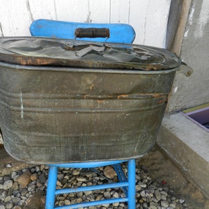 May include: A vintage copper wash tub with a wooden handle on the lid. The tub is sitting on a blue wooden stool.