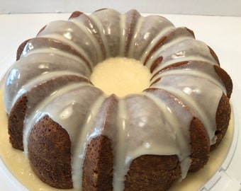 May include: A glazed bundt cake with a white glaze. The cake is on a white plate.