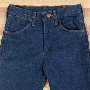 May include: A pair of dark blue denim jeans with a copper button and stitching detail.