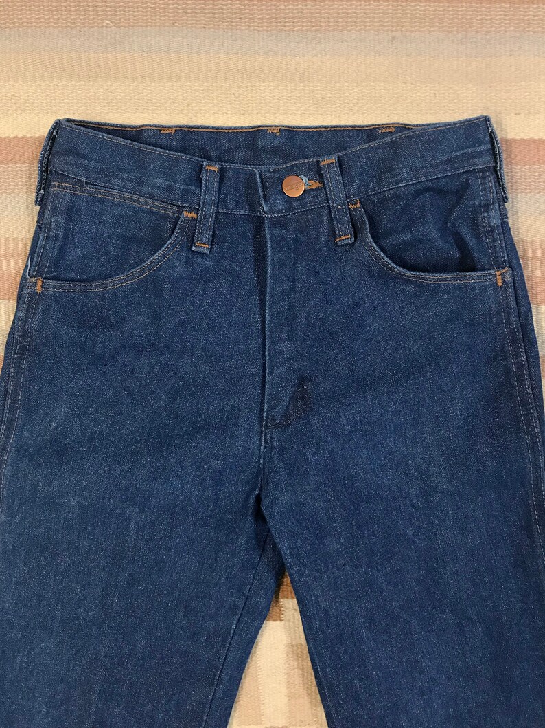 May include: A pair of dark blue denim jeans with a copper button and stitching detail.
