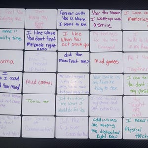 Peut inclure: Une collection de 20 cartes carrées blanches avec des messages manuscrits de différentes couleurs. Les messages portent sur l'amour, les relations et le développement personnel. Certains des messages incluent "Je sens que tu me juges", "J'aime nos souvenirs", "J'ai besoin de temps de qualité", "Contrôle mental", "Je peux dire que tu ne juges pas mon passé", "J'ai besoin de contact physique", et "Les addictions me tiennent occupé en ce moment".