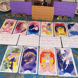 Puede incluir: Un despliegue de cartas de tarot con mensajes escritos a mano en tarjetas blancas colocadas delante de ellas. Los mensajes incluyen "Estoy tan atraída por ti", "Hablar con ellos siempre me calma, ¿por qué estoy en mi cabeza otra vez?", "Espero que sepas lo especial que eres para mí", "Tengo remordimientos de mi pasado, tengo miedo de repetir", "Estoy ocultando mis sentimientos y actuando con frialdad", "Estoy abierta a esta nueva vida contigo, pero estoy fingiendo que mi vida es feliz y satisfactoria, pero en el fondo quiero todo", "Quiero que luches por mi atención".