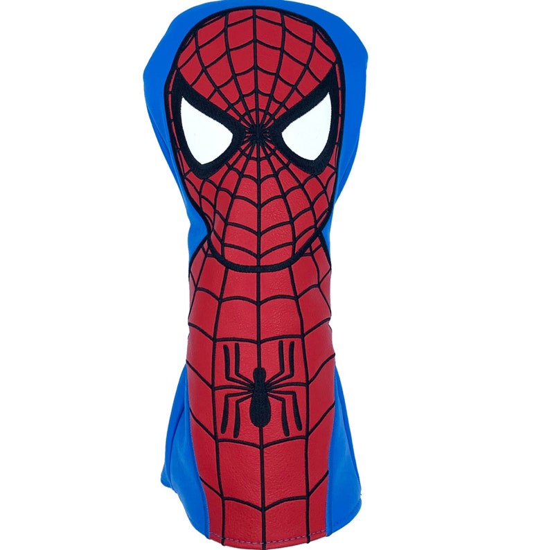 May include: A golf club head cover featuring the design of Spider-Man. The cover is primarily red with a black spiderweb pattern and a black spider emblem. The top and back are blue, and the eyes are white.