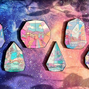 May include: Six colorful enamel pins shaped like geometric crystals. Each pin features a different cityscape scene with a whimsical, cartoon-like style. The pins are set against a galaxy-themed background.
