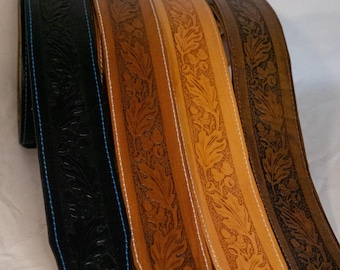 Peut inclure: Quatre sangles de guitare en cuir avec un motif floral en relief. Les sangles sont dans différentes nuances de brun, dont une noire. Les sangles ont un détail de couture blanche.