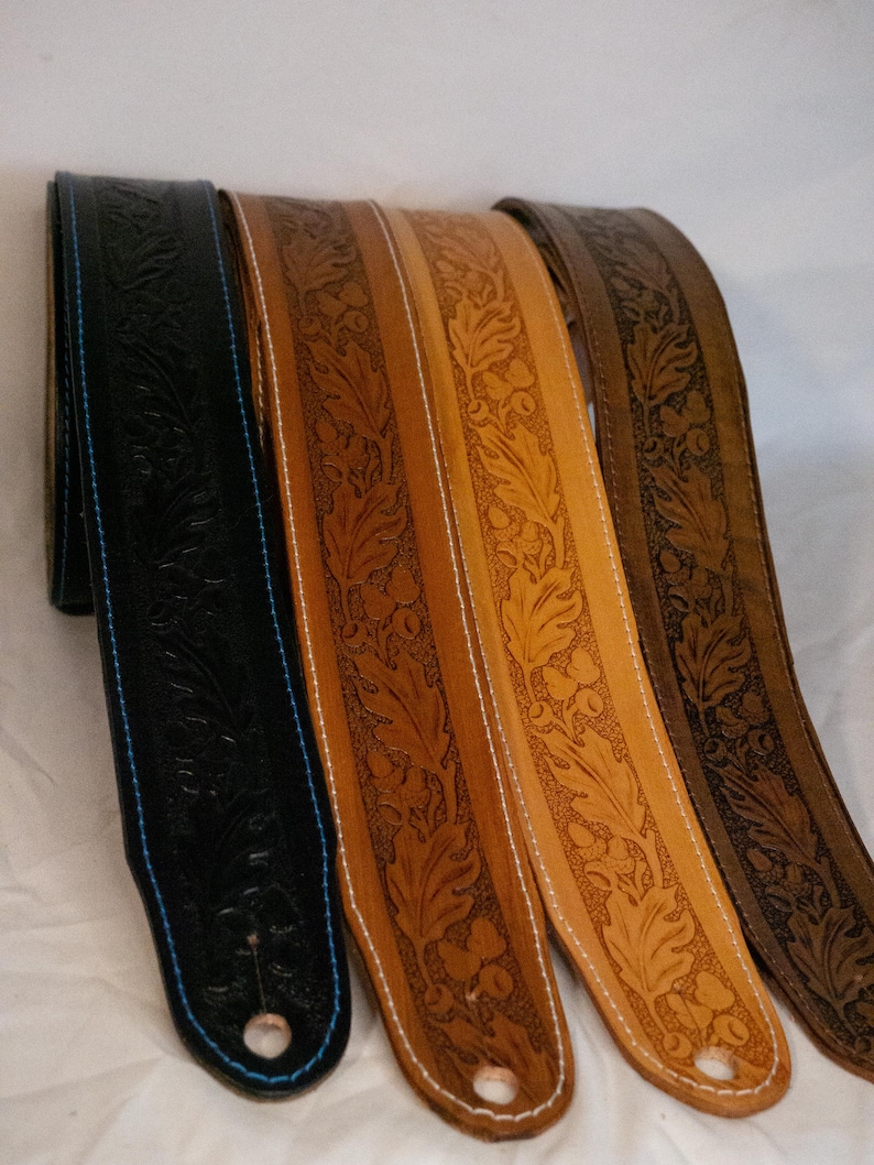 Puede incluir: Cuatro correas de guitarra de cuero con un dise&ntilde;o floral en relieve. Las correas son de diferentes tonos de marr&oacute;n, una de ellas es negra. Las correas tienen un detalle de costura blanca.