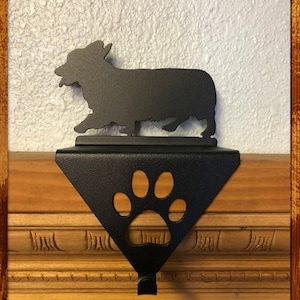 May include: Black metal stocking holder shaped like a paw print with a silhouette of a Corgi dog on top.