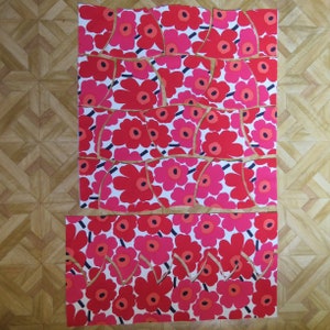 May include: A collection of fabric scraps with a red and white floral pattern. The fabric is cut into various shapes and sizes.