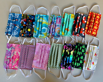May include: A collection of 14 colorful fabric face masks with various patterns, including a cat, science, flowers, and geometric designs.