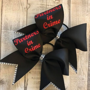 May include: Two black cheer bows with silver glitter trim and red text that reads "Partners in Crime".