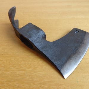 May include: A black metal axe with a curved handle and a sharp blade. The axe has a small, rectangular hole in the handle.